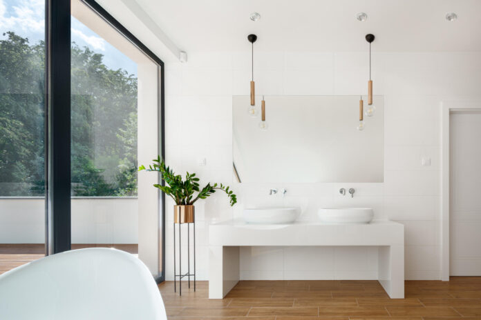 Elegant white bathroom interior with big window, wooden floor and two washbasins