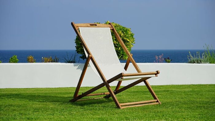 A small wooden lawn chair décor in front of the ocean.