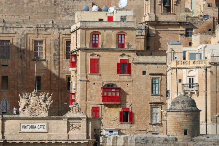 A real estate property in Malta featuring a stone building with red shutters.