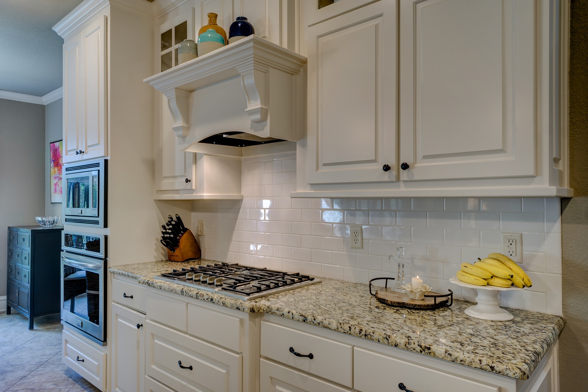 A kitchen with white cabinets and granite counter tops, understanding cabinet refacing.