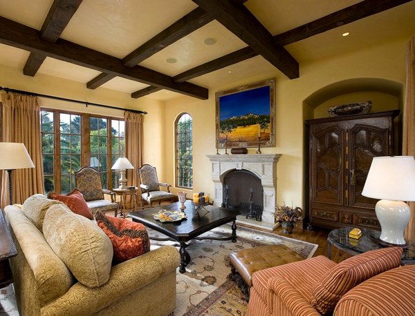 A Tuscan living room with an ornate fireplace and wooden beams.