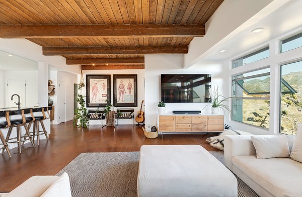 A living room with white furniture and wood beams.