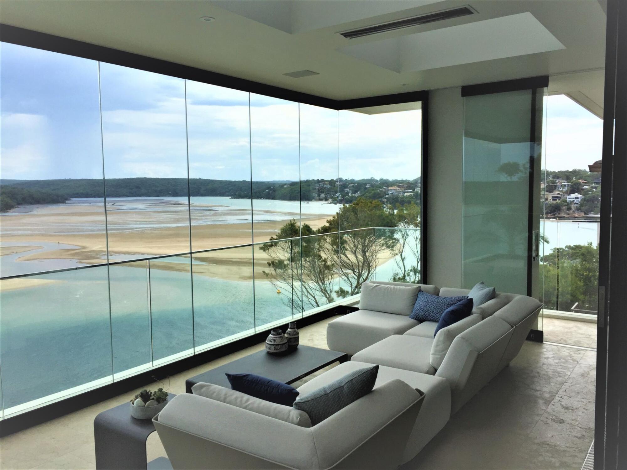 A living room with large architectural glass windows overlooking a lake.