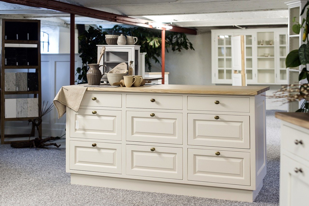 A white kitchen island with drawers in a room that features antique white kitchen cabinets.