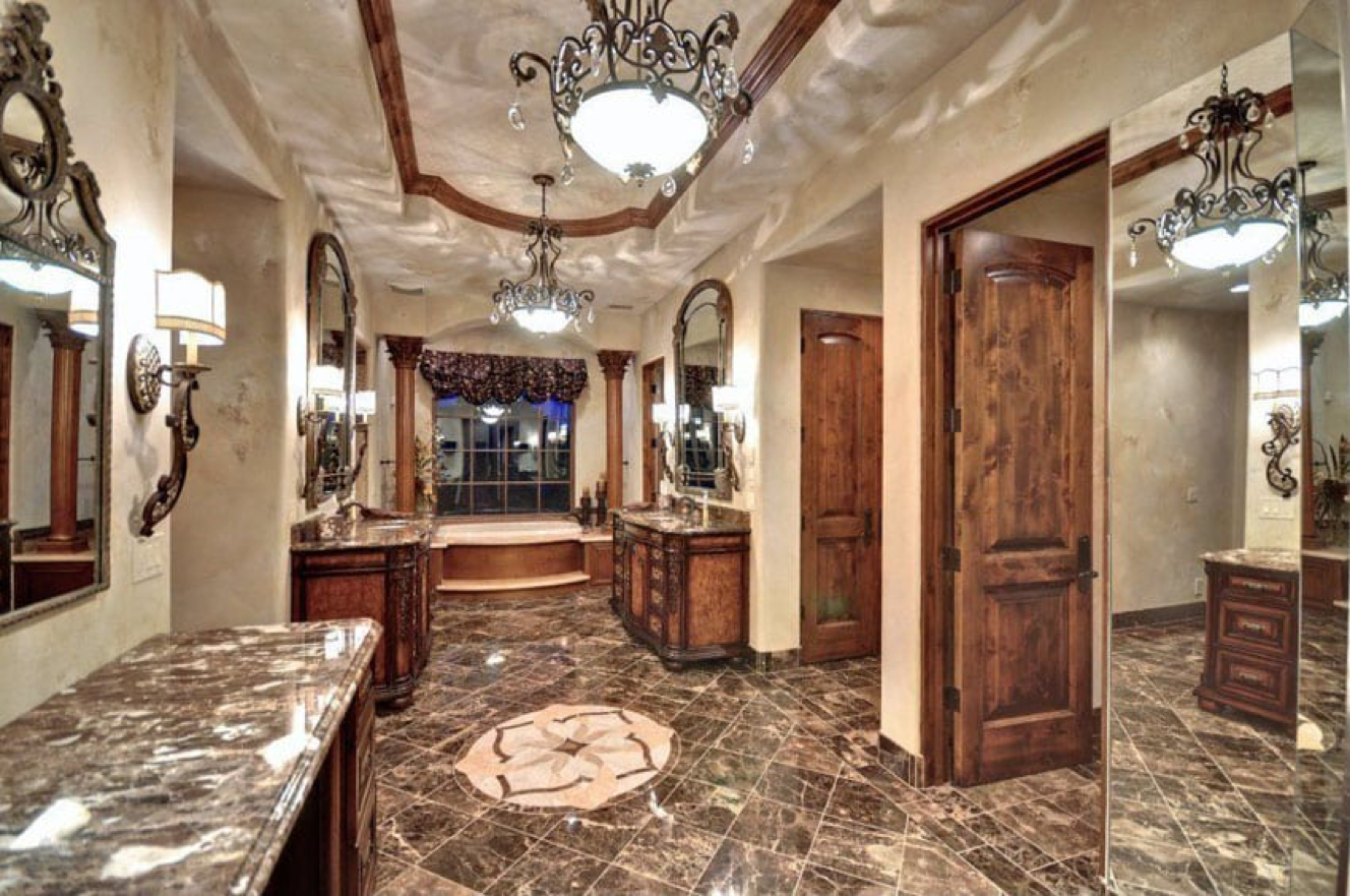 A Craftsman bathroom featuring marble counter tops and a chandelier.
