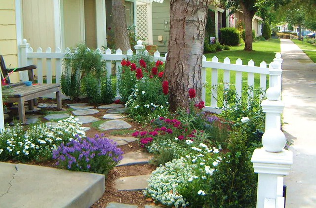 A small front yard with flowers and a white picket fence.