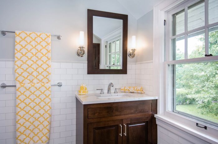 A white bathroom with penny tile flooring and a window.