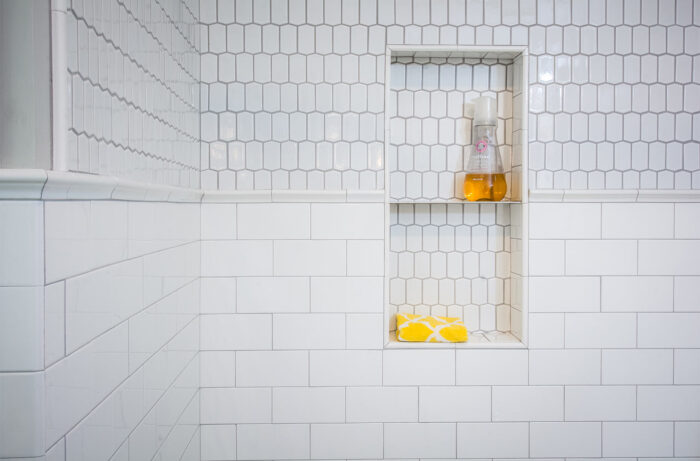 A white tiled penny tile bathroom with a shelf and lemons.
