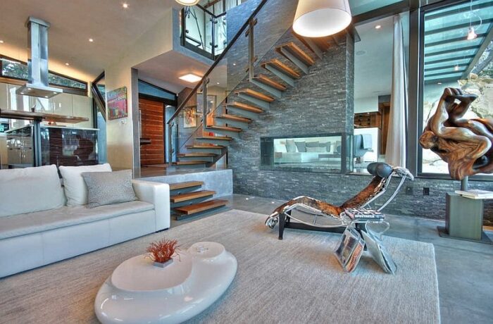 A modern sunken living room with a glass staircase.
