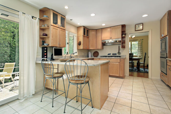A kitchen with a door leading to a patio and a kitchen peninsula.