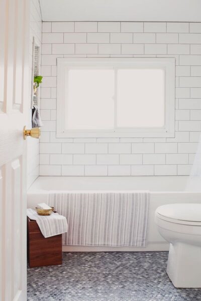 A white tile floor and a toilet in a Craftsman bathroom.
