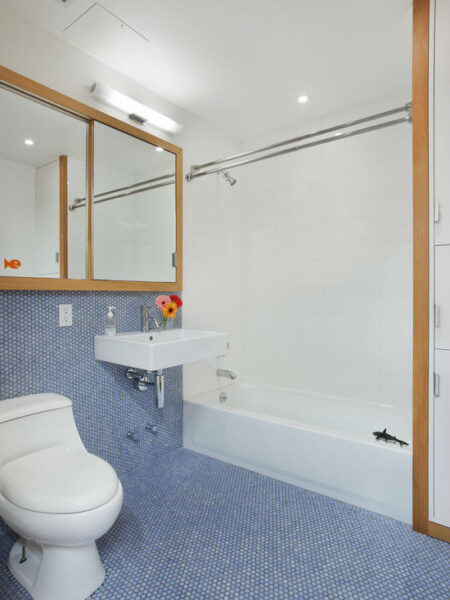 A blue penny tiled bathroom with a toilet and sink.