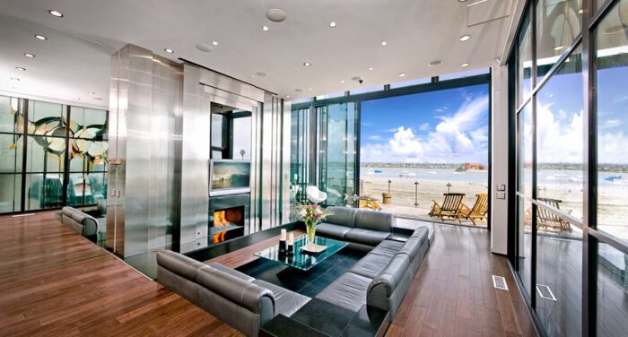 A sunken living room with glass walls and a view of the beach.