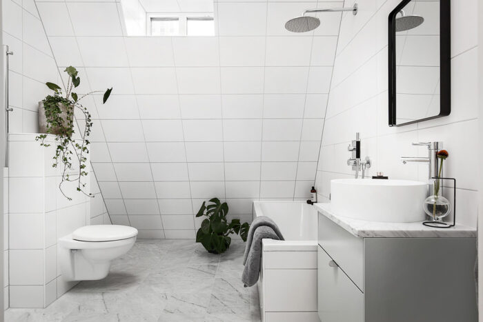 A white tiled Scandinavian bathroom with a toilet and sink.