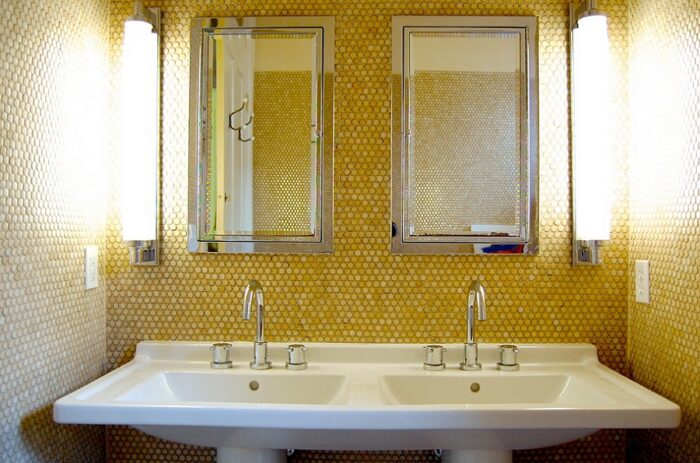 A penny tile bathroom with two sinks and two mirrors.