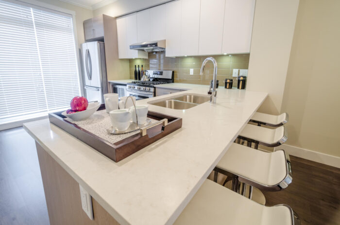 A kitchen with white counter tops and a kitchen peninsula.