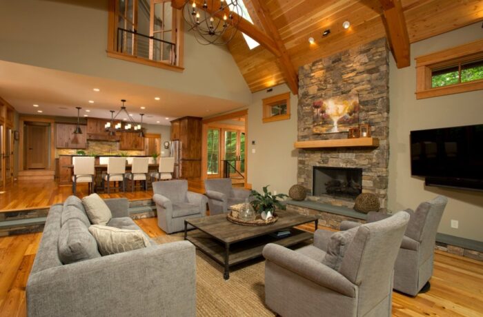 A sunken living room with wood beams and a stone fireplace.