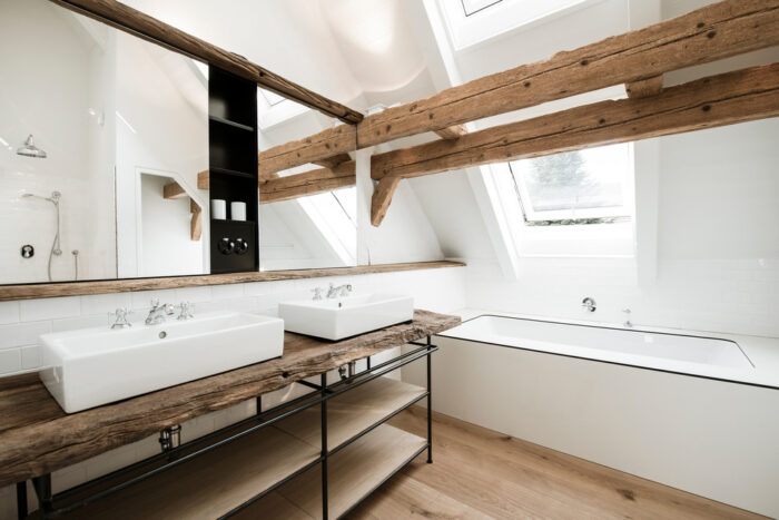 A Scandinavian bathroom with wooden beams and a bathtub.