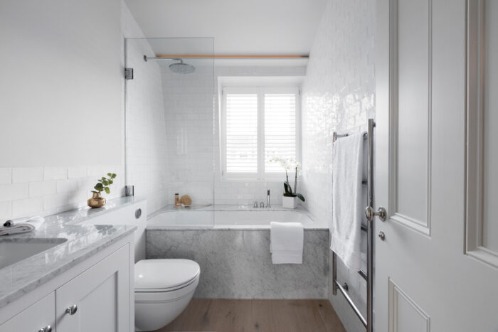 A Scandinavian bathroom with wooden floors and a bathtub.