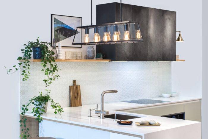 A modern kitchen with a sink and a light fixture, featuring a kitchen peninsula.