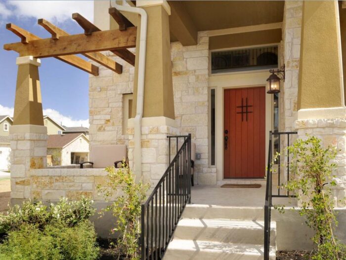 Grand columns and iron details accentuate this rustic red door and add Southwestern style.