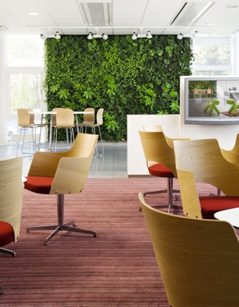 A green wall enhances the architecture of an office space with chairs.