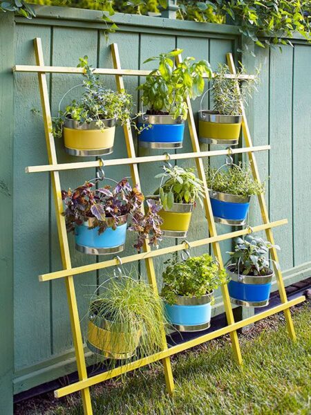 A hanging garden of potted plants on the side of a fence.