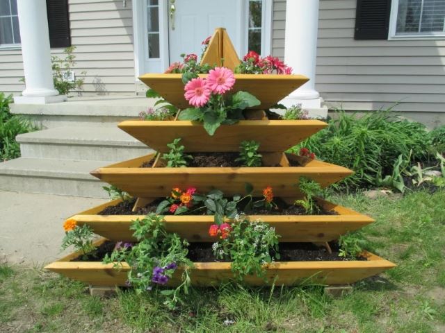 A wooden triangular planter with flowers, creating a hanging garden.