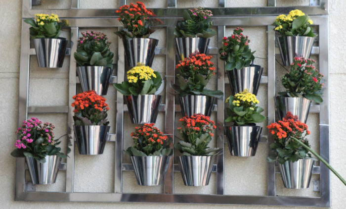 A metal hanging planter with several pots of flowers.