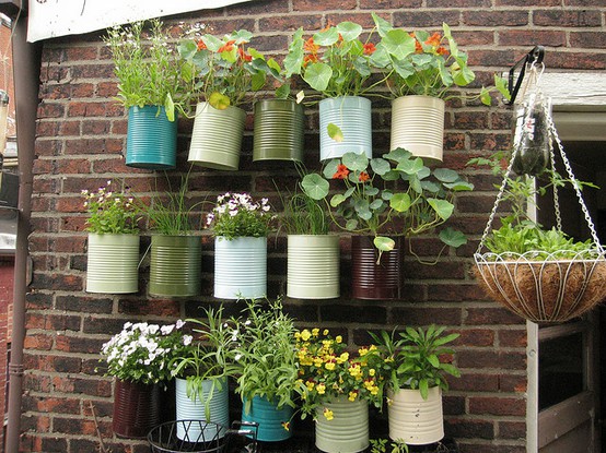A group of tin cans with hanging plants.
