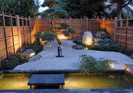 A Zen garden with a wooden fence and pond.