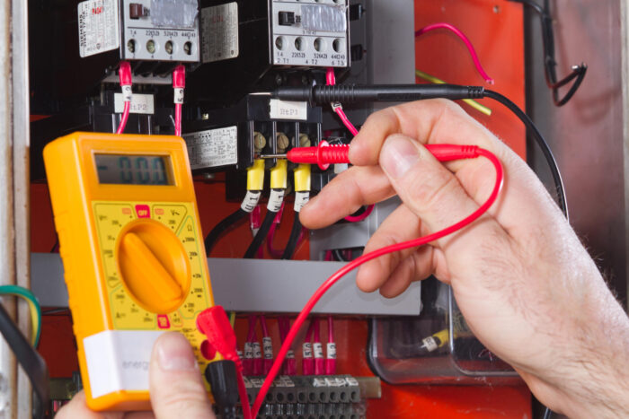 An electrician checking a circuit breaker using a multimeter.