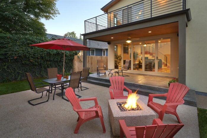 An outdoor living space with red chairs and a fire pit.
