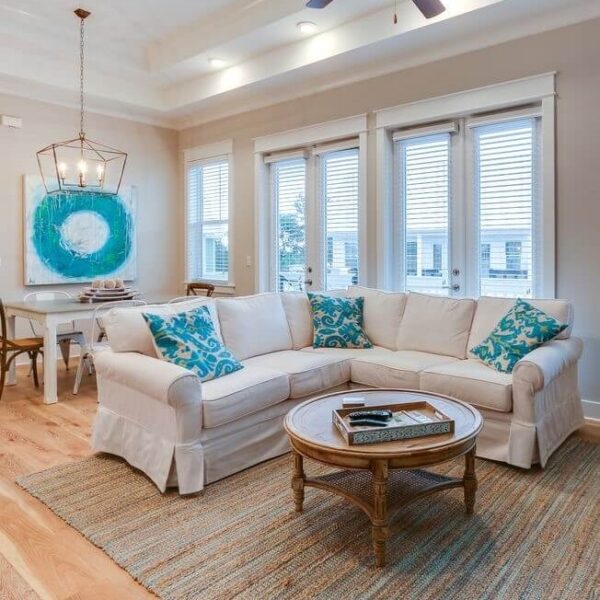 A beach-themed living room with hardwood floors and a ceiling fan.