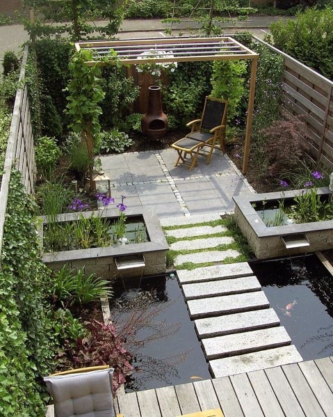 A small backyard with a wooden deck and a pond, incorporating garden stepping stone ideas.