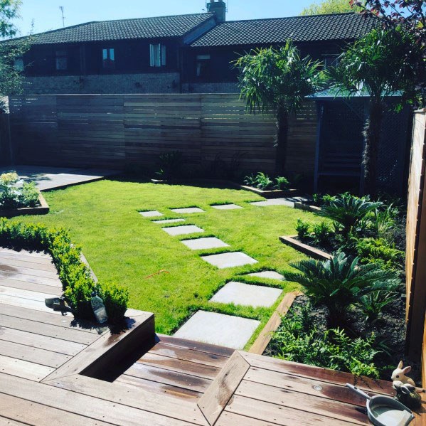 A garden with wooden steps and a wooden deck, featuring unique stepping stone ideas.