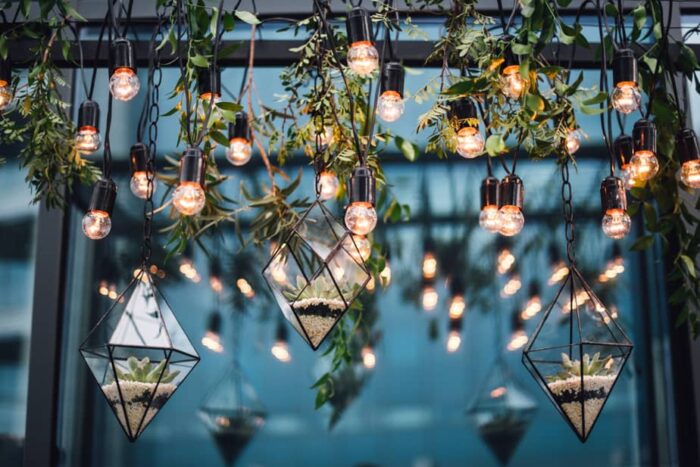 Light bulbs hanging from a glass ceiling, creating a unique balcony garden idea.