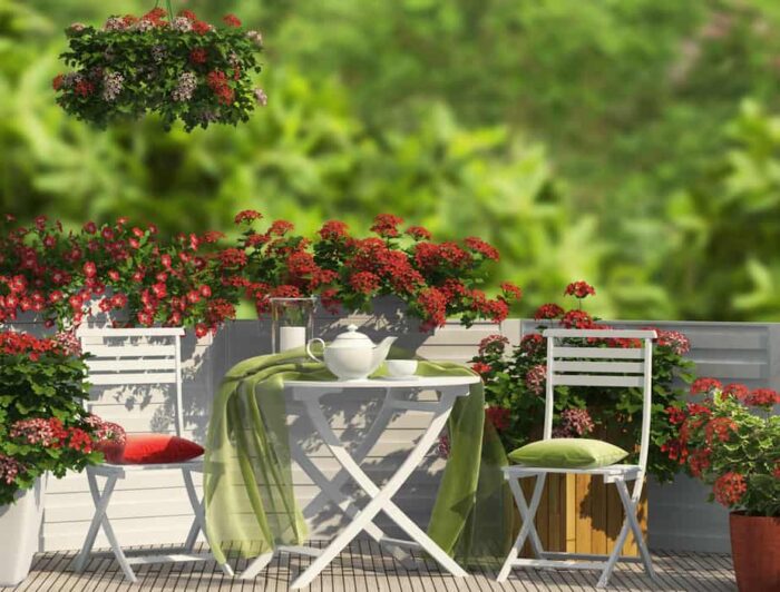 A balcony with a table, chairs, and flowers.