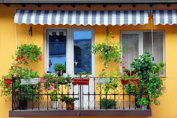A balcony with potted plants, an awning, and a garden idea.