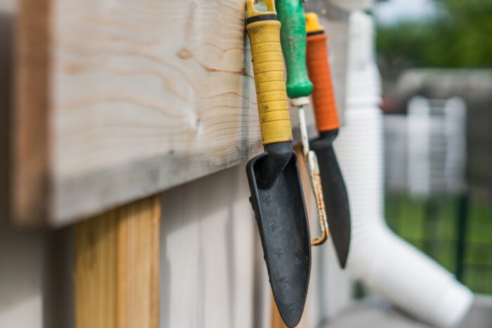 A collection of gardening tools displayed on a wooden wall.