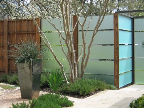 An architecturally designed garden with a glass fence and a potted plant.