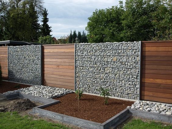 A backyard with a wooden fence and rocks, showcasing the design of its architecture.