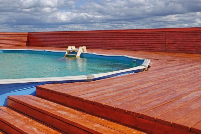 An architecturally designed wooden deck next to a swimming pool.