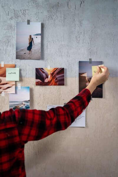A woman adorning a wall with pictures for decor.