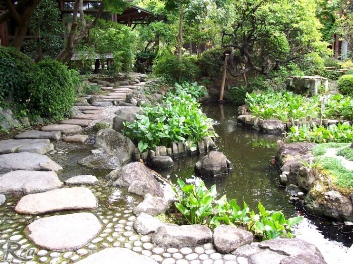 A Zen garden with stepping stones leading to a pond.