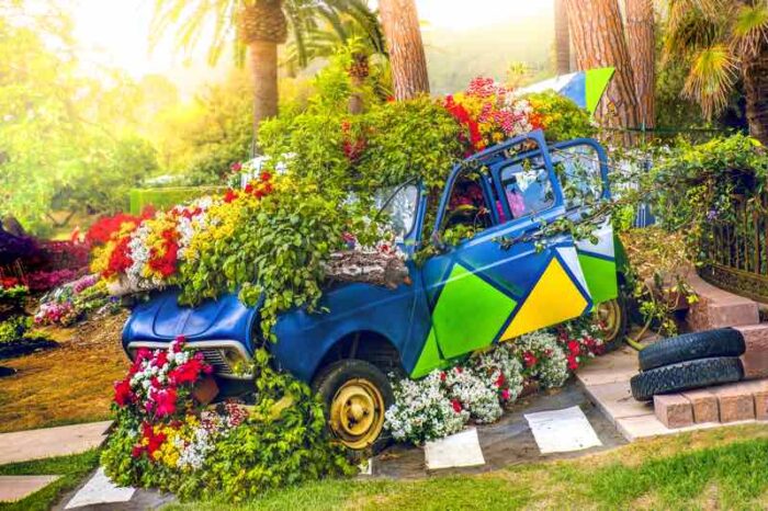 A flower-covered car in a garden.