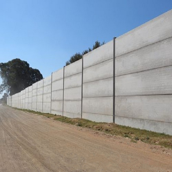 A architectural concrete wall next to a dirt road.