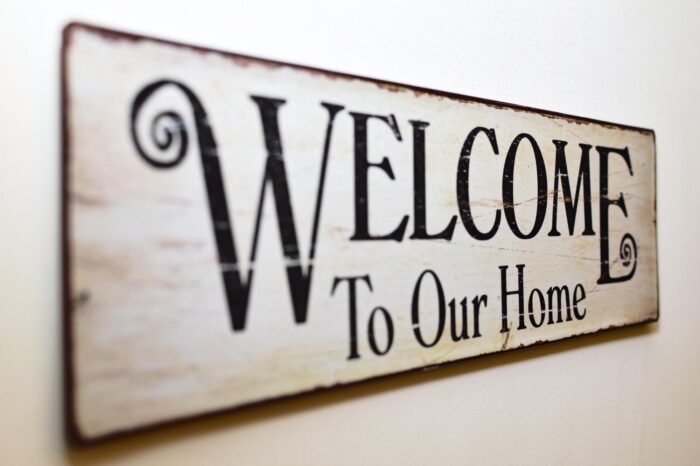 Welcome to our home sign featuring beautiful wallpaper decor.