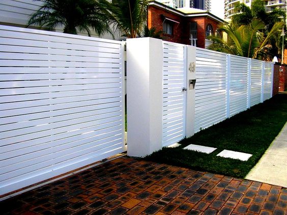 A white fence with white slats enhancing the architectural design of a house.