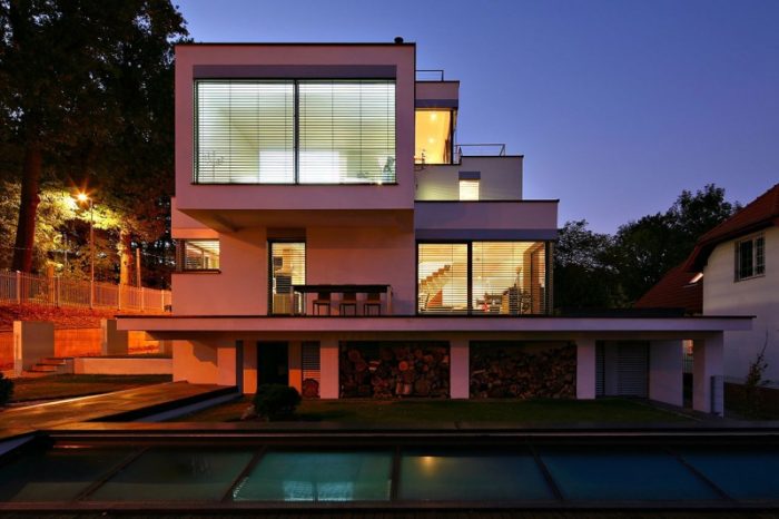 A contemporary house with a swimming pool at night.